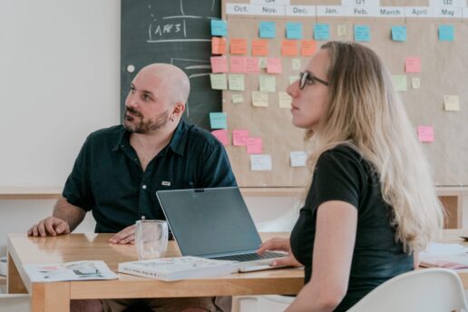 Two Vetica team members in a meeting in front of a roadmap with sticky notes.