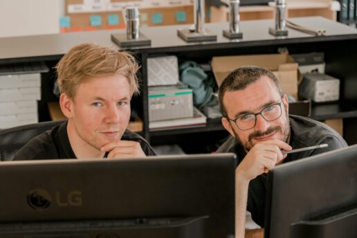 Two Vetica experts in front of computer screens in a creative workspace.