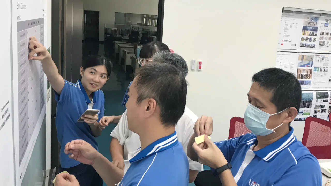 Ein Team von LIWIN-Mitarbeitern in blauen Firmen-Poloshirts steht vor einem Whiteboard und bewertet Markenattribute mit kleinen Aufklebern.